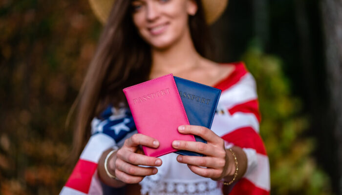 Happy woman in a straw hat with an american flag and passports i